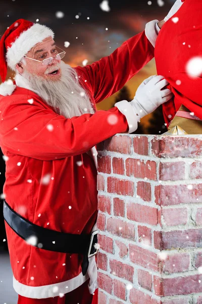 Santa claus plaatsen geschenkdoos in schoorsteen — Stockfoto