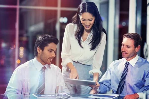 Businesswoman discussing with colleagues over tablet — Stock Photo, Image