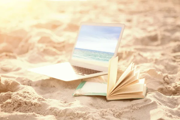 Open book and laptop on sand at beach — Stock Photo, Image