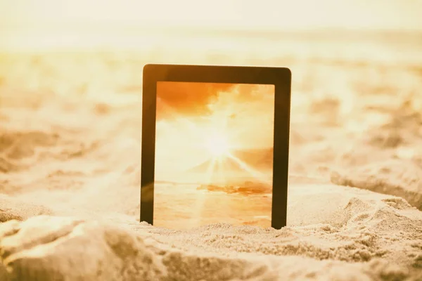 Digitales Tablet auf Sand gehalten — Stockfoto