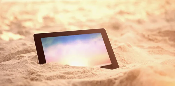 Tableta digital mantenida sobre arena en la playa — Foto de Stock