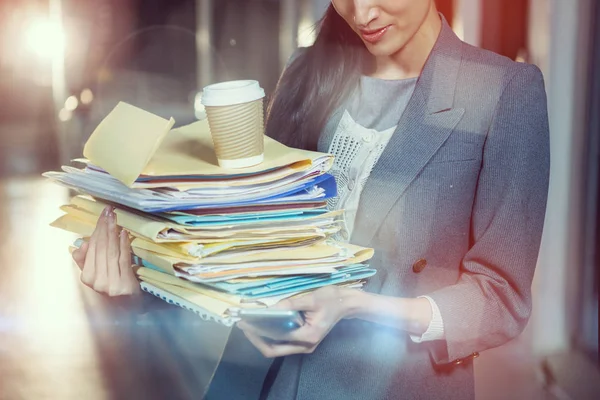 Businesswoman carrying stack of file folders