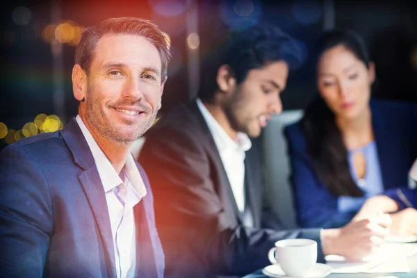 Empresario sonriendo mientras sus colegas interactúan — Foto de Stock