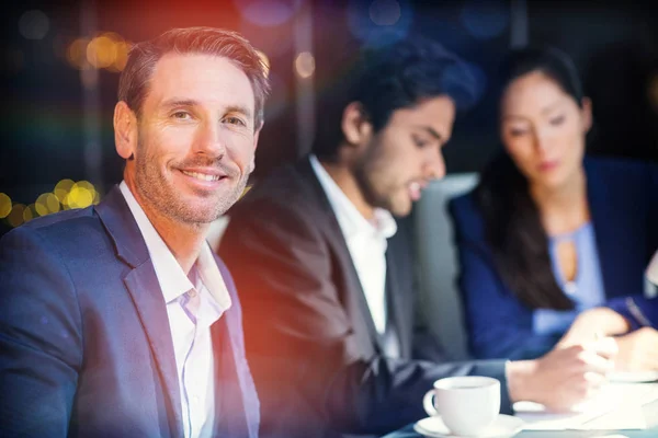 Empresario sonriendo mientras sus colegas interactúan —  Fotos de Stock