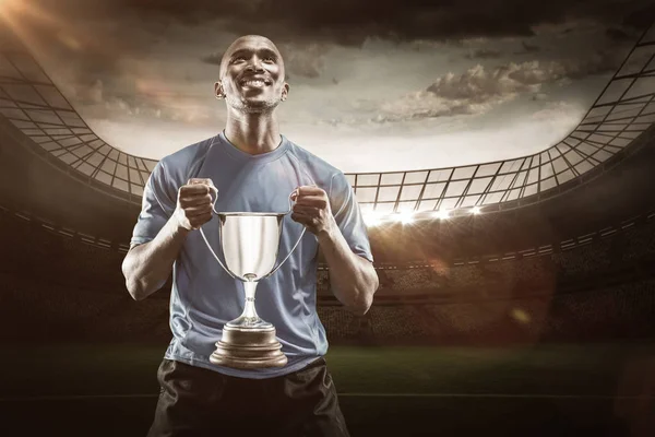 Atleta segurando troféu olhando para cima — Fotografia de Stock