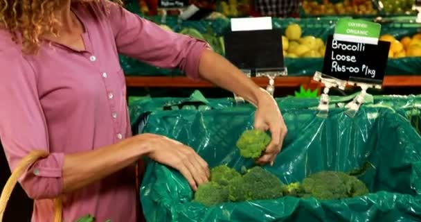 Улыбающаяся женщина покупает брокколи — стоковое видео