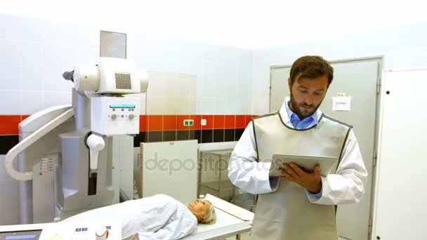 Врач-мужчина, использующий цифровой планшет в рентгеновской комнате — стоковое видео