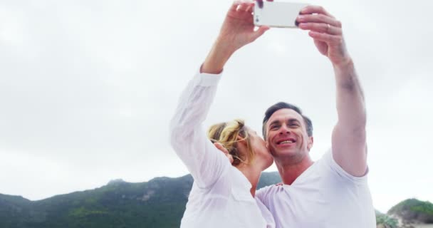 Pareja madura tomando una selfie en la playa — Vídeo de stock