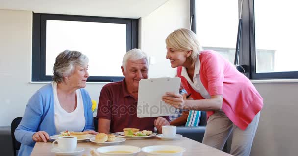 Dietician assisting breakfast to senior couple — Stock Video