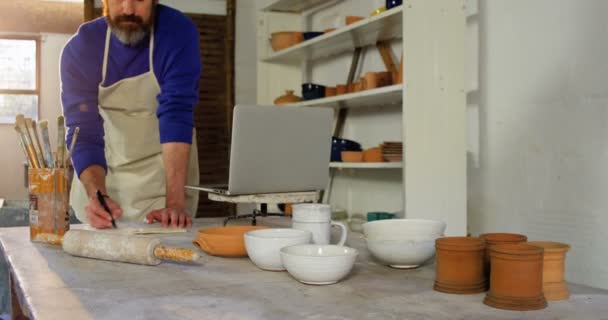 Mannelijke potter op een boek schrijven — Stockvideo