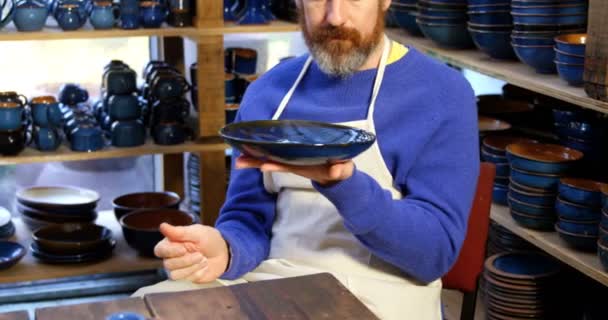 Male potter examining a earthenware bowl — Stock Video