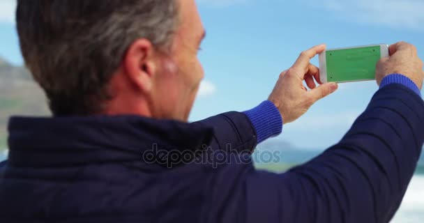 Зрілий чоловік фотографує вид з телефону — стокове відео
