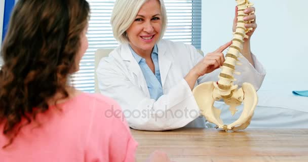 Médico explicando el modelo de columna vertebral al paciente femenino — Vídeos de Stock