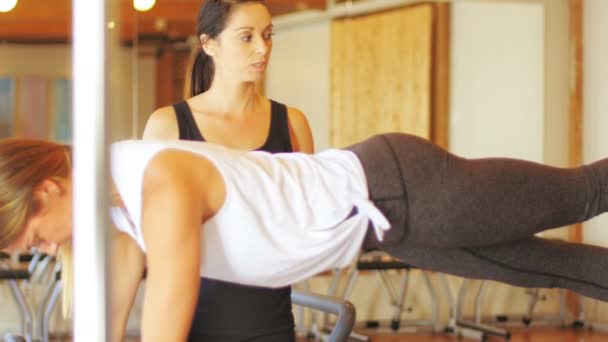Жінка-тренер, що допомагає жінці з фізичними вправами — стокове відео