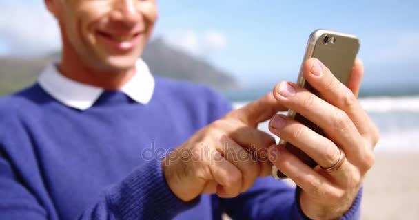 Człowiek przy użyciu telefonu na plaży — Wideo stockowe