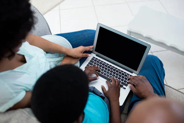 Parents et fils utilisant un ordinateur portable dans le salon — Photo