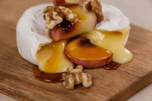 Queijo coberto com nozes, frutas e molho — Fotografia de Stock