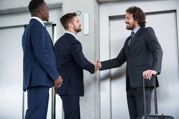 Empresarios dándose la mano mientras esperan el ascensor —  Fotos de Stock