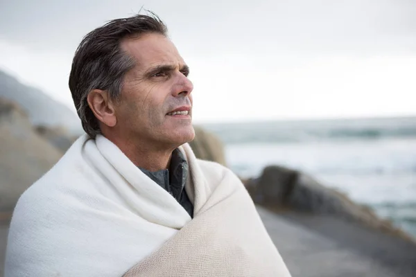 Nachdenklicher Mann in Schal gehüllt am Strand — Stockfoto