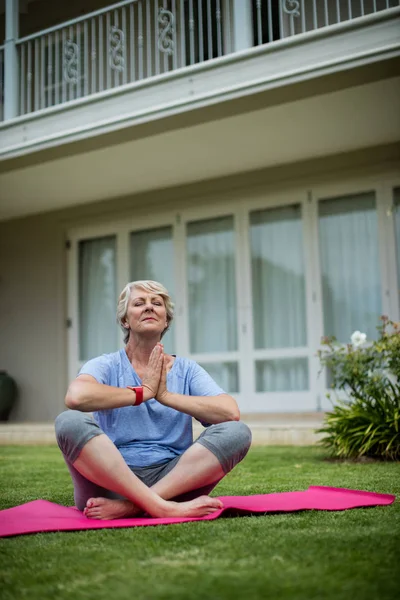 Mujer mayor practicando yoga en alfombra de ejercicio — Foto de Stock