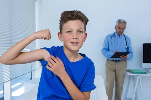 Chico flexionando sus bíceps en la clínica — Foto de Stock