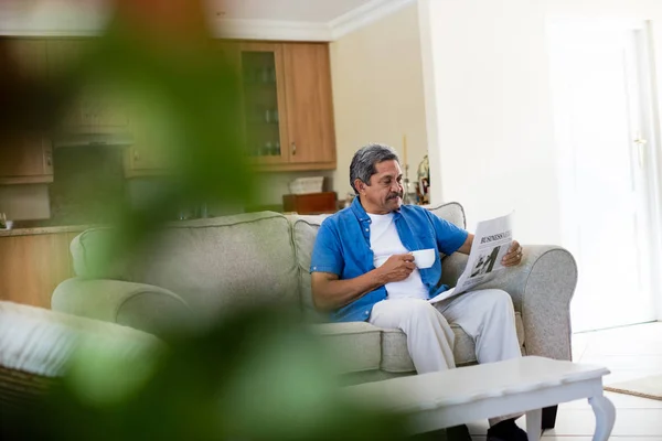 Uomo anziano che legge giornale mentre prende un caffè — Foto Stock