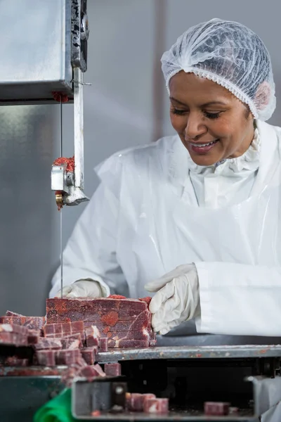 Carniceiro fêmea cortando carne crua — Fotografia de Stock