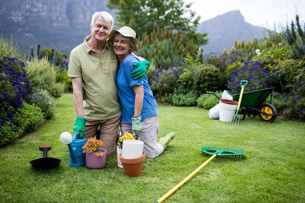Äldre par embracing medan trädgårdsarbete — Stockfoto