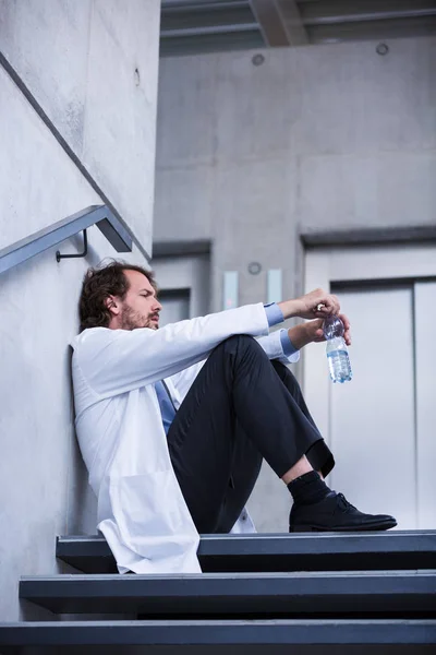 Беспокойный доктор сидит на лестнице — стоковое фото