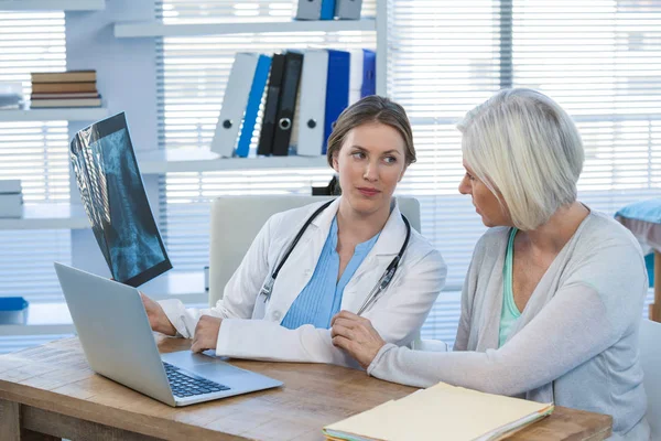 Vrouwelijke arts x-ray verslag uit te leggen aan patiënt — Stockfoto