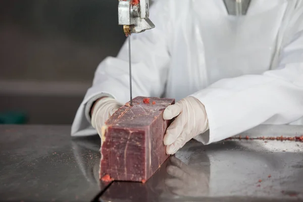 Carniceiro fêmea cortando carne crua — Fotografia de Stock
