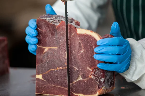 Female butcher cutting raw meat — Stock Photo, Image