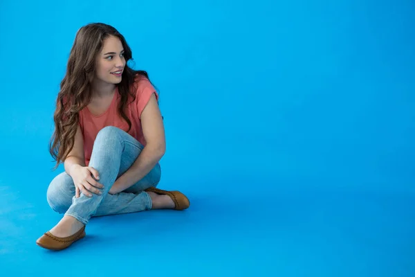 Mujer sentada sobre fondo azul —  Fotos de Stock