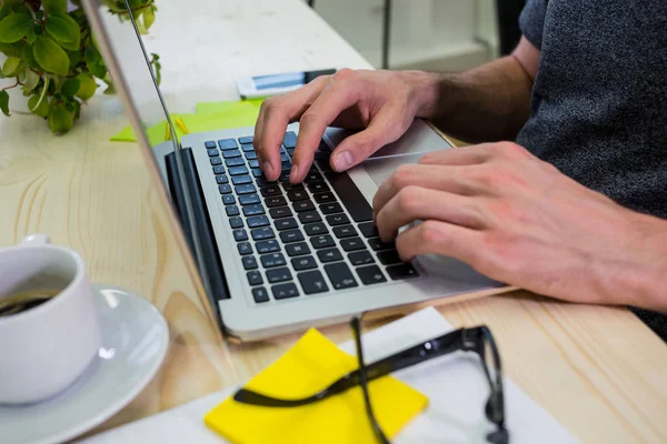 Grafisk formgivare använder laptop vid sitt skrivbord — Stockfoto