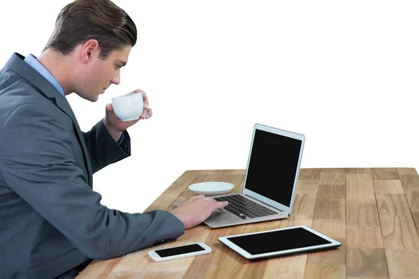 Businessman having coffee while using laptop — Stock Photo, Image