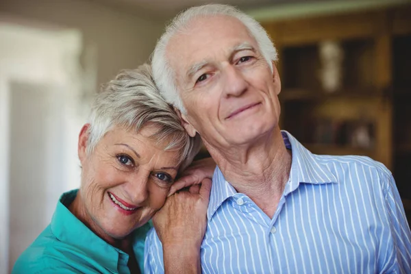 Старшая пара улыбается в гостиной — стоковое фото