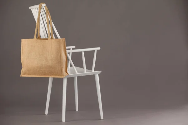 Beige fabric bag hanging on white chair