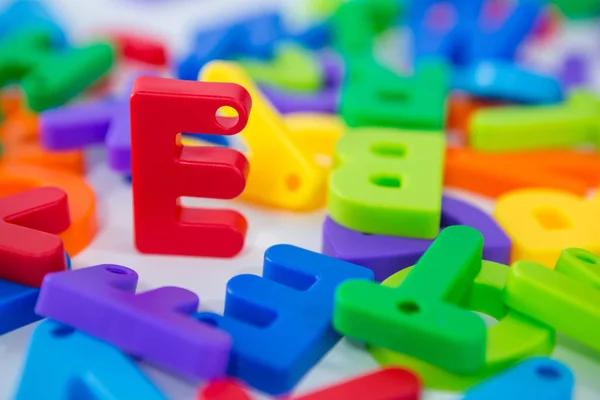 E alfabet staande tussen speelgoed alfabet — Stockfoto