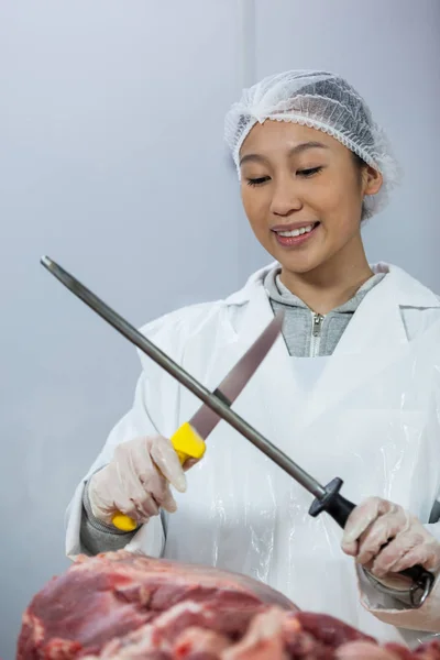 Female butcher sharpening her knife — Stock Photo, Image