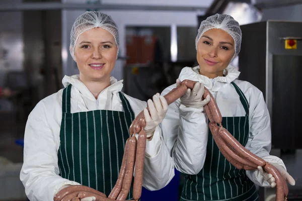 Carniceiros fêmeas processando salsichas — Fotografia de Stock