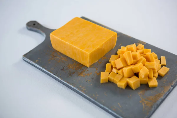 Block and cubes of cheese on chopping board — Stock Photo, Image