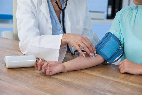 Médico feminino verificando a pressão arterial de um paciente — Fotografia de Stock