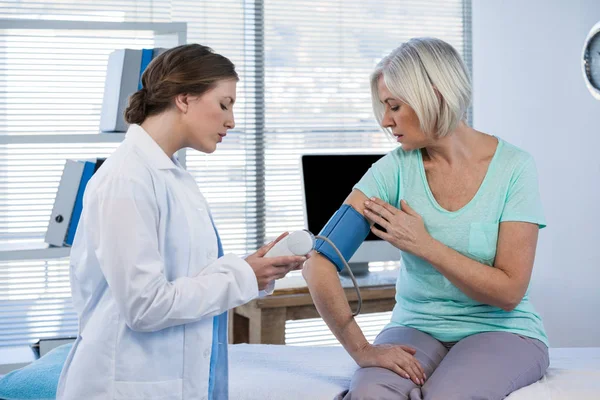 Жінка-лікар, що перевіряє артеріальний тиск пацієнта — стокове фото