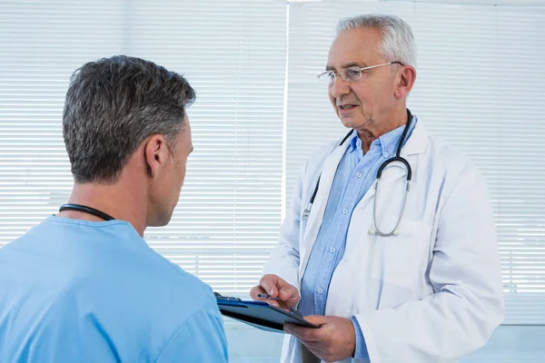 Doctor and surgeon discussing over clipboard — Stock Photo, Image