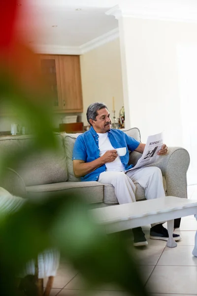 Homem sênior lendo jornal enquanto toma café — Fotografia de Stock