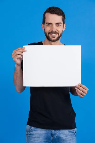 Yakışıklı adam boş bir afişini holding — Stok fotoğraf