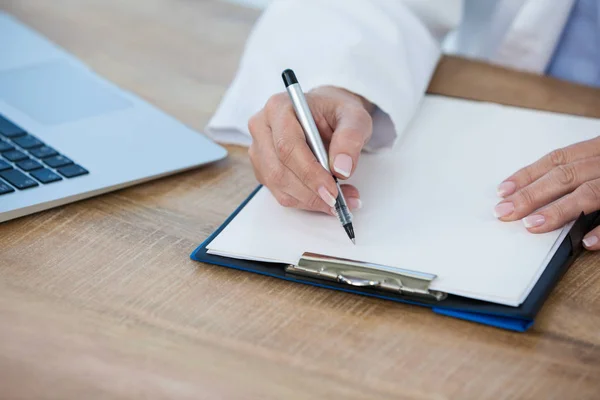 Vrouwelijke arts schrijven op Klembord — Stockfoto