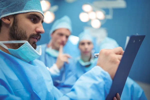 Команда хирургов обсуждает это за планшетом — стоковое фото