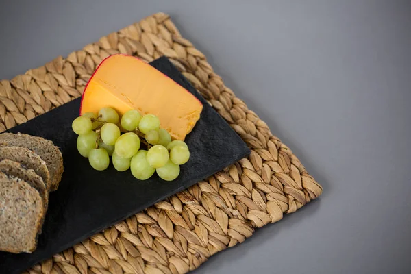 Queso Gouda y uvas en plato de pizarra —  Fotos de Stock