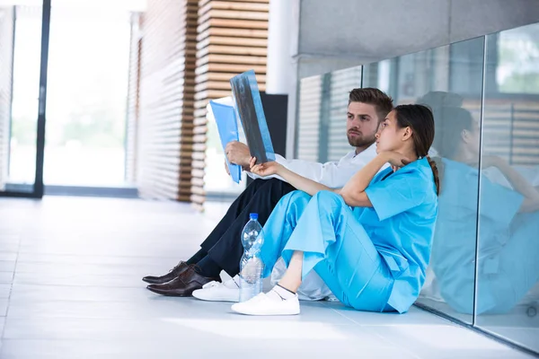 Stressad läkare och sjuksköterska sitter på golvet — Stockfoto